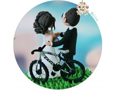 Figurine de tort pentru nunta - Mirele si Mireasa stau langa bicicleta lor