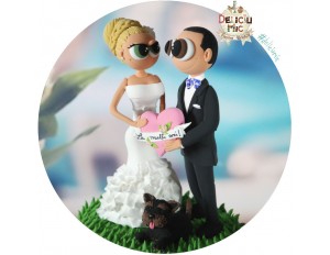 Figurine de tort pentru nunta - Mirii tin in mana o inimioara roz pe care scrie "La multi ani"