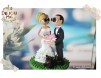 Figurine de tort pentru nunta - Mirii tin in mana o inimioara roz pe care scrie "La multi ani"